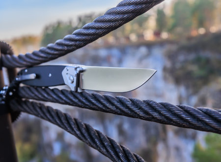 Knife on a metal cable against the background of a rockの写真素材