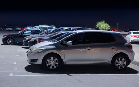 Cars in an illuminated parking lot at night in the cityの写真素材