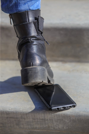 Smartphone on concrete steps under a woman's shoeの写真素材