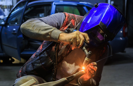 Welder repairing a car part in a car repair shopの写真素材