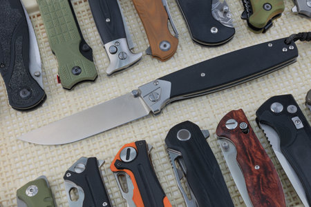 Many folding knives on a textured background close-upの写真素材