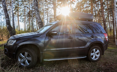 SUV with a roof rack in the forest in the sun close-upの写真素材
