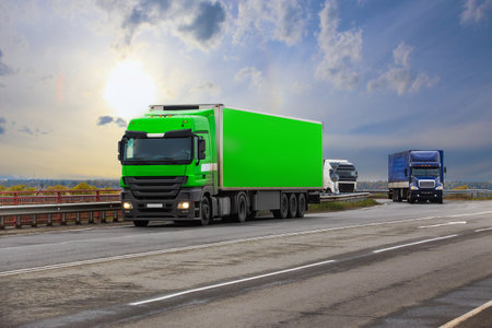 Trucks carry cargo on a country highway against the backdrop of a beautiful sunriseの写真素材