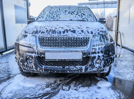 Car at the car wash in the foam close-up front viewの写真素材