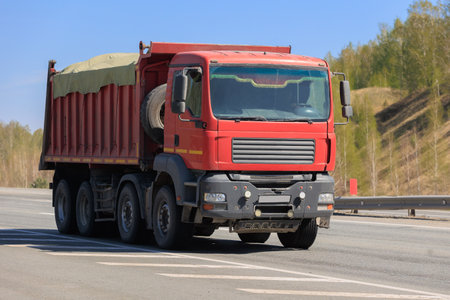 Dump truck moves on a country road close-upの写真素材