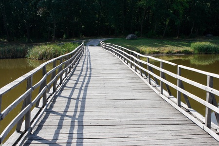 Wooden bridge across the river against the backdrop wood of deciduous trees