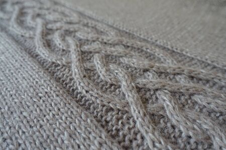 Close-up of grey handmade knit fabric with plait pattern