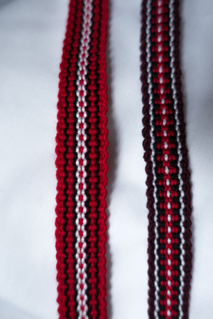Two narrow woven tapes in with ethnic pattern in red, purple, black and whiteの写真素材