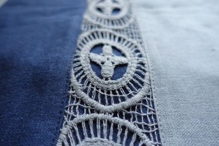 Macro of lace on blue linen fabric