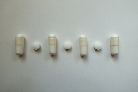 View of row of white magnesium citrate capsules and vitamin K2 tablets from above