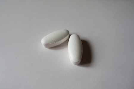 Two big white oblong caplets of calcium citrateの写真素材