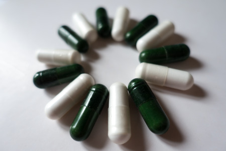 Daisy like shape made of green multivitamins and white magnesium capsulesの写真素材
