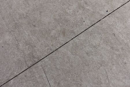 Diagonal joint between two light grey concrete slabs