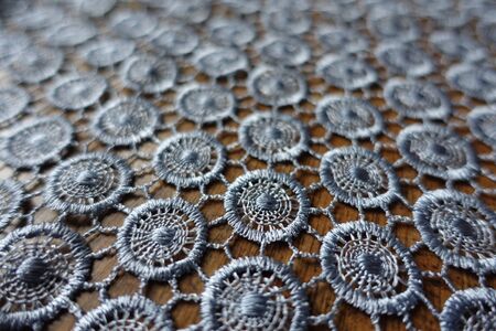 Close view of silver gray crochet lacy fabric on woodの写真素材