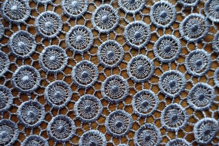 Texture of silver gray crochet lacy fabric on wood from above