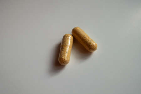Two orange cellulose capsules of multivitamins dietary supplementの写真素材