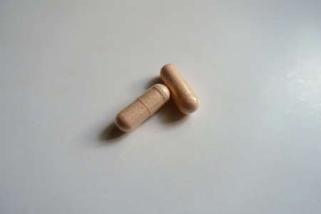Close view of two pink capsules of probiotic dietary supplement