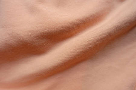 Pair of soft folds on apricot colored simple cotton jersey fabricの写真素材