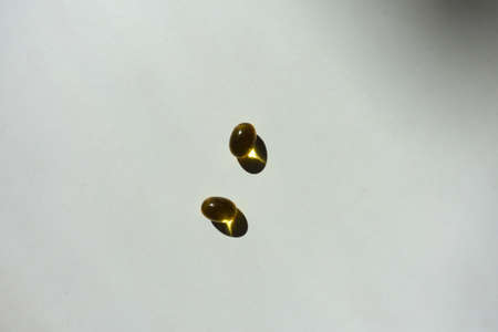 Top view of two yellow softgel capsules of vitamin A (retinyl palmitate)の写真素材