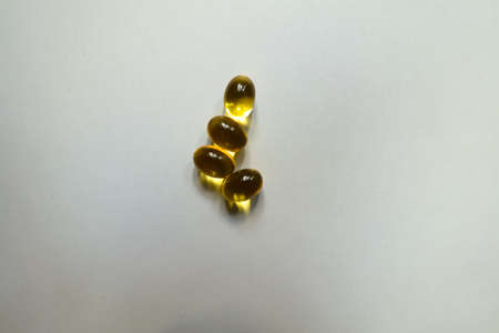 4 yellow softgel capsules of vitamin A (retinyl palmitate)の写真素材
