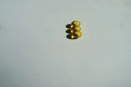 Batch of three yellow softgel capsules of vitamin A (retinyl palmitate)の写真素材