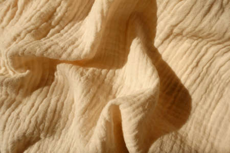 thin beige cotton muslin fabric in soft folds