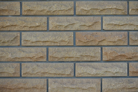 Texture of beige brick veneer wall with grey mortar joints