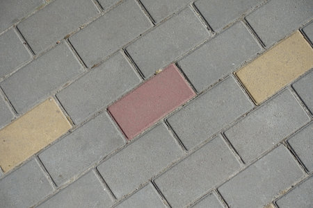 Closeup of gray, pink and yellow concrete pavement with stretcher bond pattern