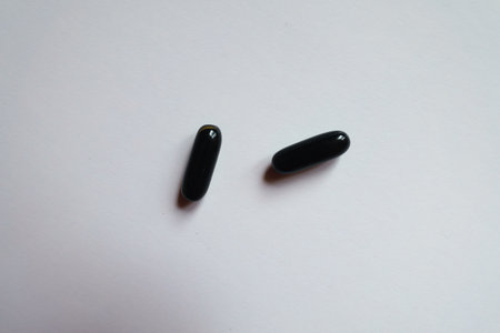 View of two black softgel capsules of activated charcoal from above
