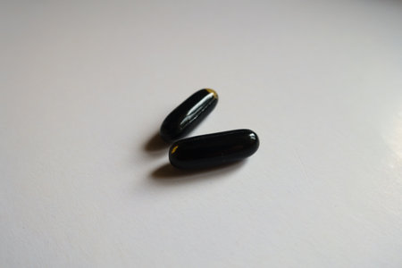 Close shot of two black softgel capsules of activated charcoal
