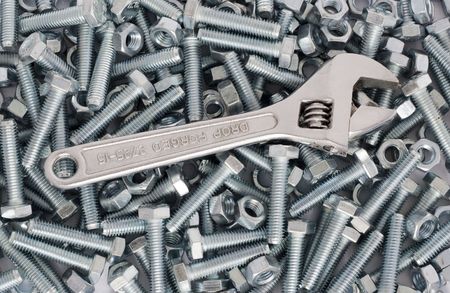 Screw wrench (monkey wrench) in the background of nuts and boltsの写真素材