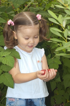 A smiling cute girl holding the palms of raspberriesの写真素材