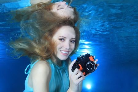 Woman underwater with photo camera の写真素材