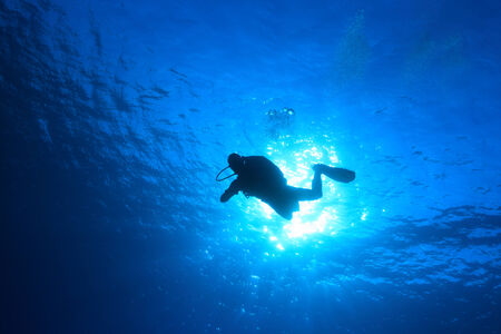 Silhouette of scuba diver in the blue water