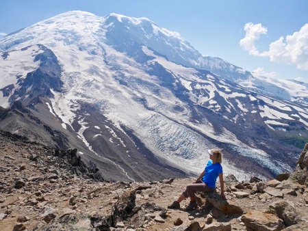 Woman sitting by mountain. Burroughs Mountain Trail, Mount Rainier National Park, Seattle, Washington, USA.の写真素材