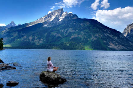 Woman meditating by Jenny Lake in Grand Tetons National Park, Jackson, Wyoming.の写真素材