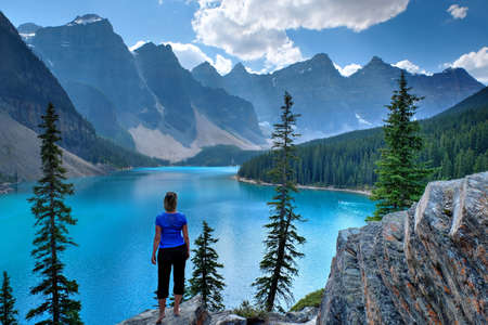 Woman on cliff looking at Moraine Lake.  Rocky Mountain. Banff National Park, Alberta, Canada.の写真素材
