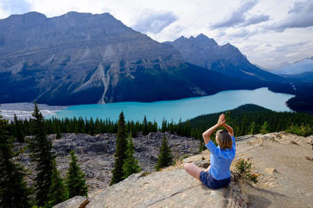 Woman in yoga pose on mountain top above Peyto lake in Rocky Mountains. Banff National Park. Alberta. Canada.の写真素材