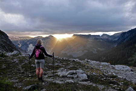 Woman watching sunrise in mountains. Lake Ann trail in Cascade Mountain. Mount Baker National Forest. Washington. USA.の写真素材