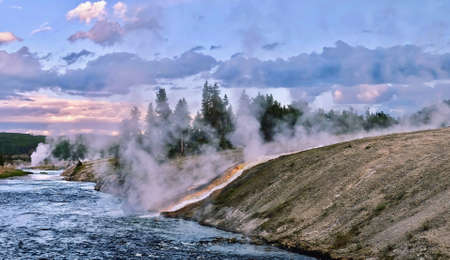 Steaming river at sunset. Hot water from the Midway Geyser Basin cascades into the Firehole River in Yellowstone National Park.  Wyoming. United States.の写真素材