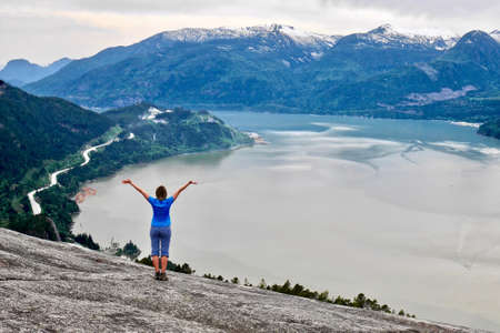 Young woman on cliff over  the ocean. Stawamus Chief Peak. Squamish. Whistler. British Columbia. Canada.の写真素材