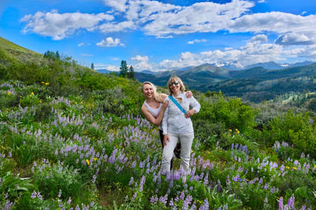 Happy smiling women hiking in meadows among wildflowers. Banff National park. Canadian Rockies. Calgary. Alberta. Canada.の写真素材