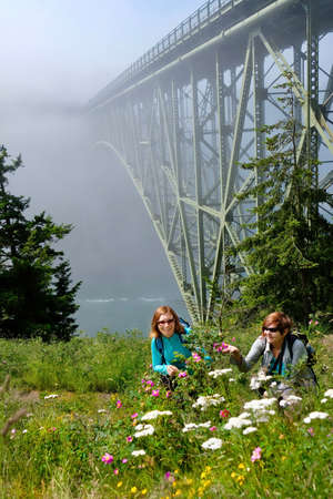 Happy women hiking by ocean in foggy morning. Deception Pass Bridge State Park.  Anacortes. Seattle. Puget Sound. Juan de Fuca Strait. Washinton. United States.の写真素材