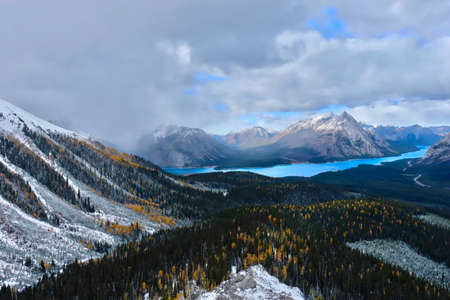 Lake in Canadian Rockies. Snowfall in mountains   with  golden larches forest. Banff National Park....
