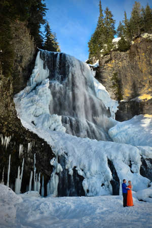 Happy couple in love near waterfall. Frozen waterfall near Callahan Park. Alexander Falls. Whistler. British Columbia. .のeditorial素材
