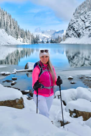 Happy smiling woman snowshoeing in mountains by alpine lake with reflections. Lake Agnes tea house trail in Banff National Park. Canadian Rockies. Alberta. Canadaの写真素材