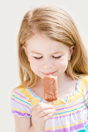 Cute blond little girl eating ice-cream in summer sunny dayの写真素材