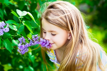 Beautiful blond little girl with long hair smelling flowerの写真素材