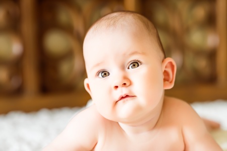Closeup portrait of a cute little baby lying on parent's bedの写真素材