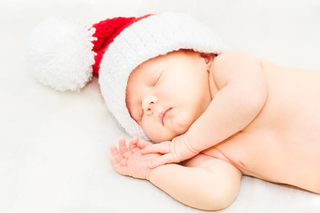 Adorable sleeping newborn baby wearing Santa Claus hat, Christmas, New Yearの写真素材